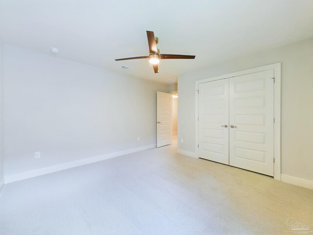 unfurnished bedroom featuring light carpet, a closet, and ceiling fan