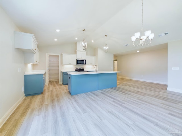 kitchen with blue cabinets, stainless steel appliances, white cabinets, light countertops, and an island with sink