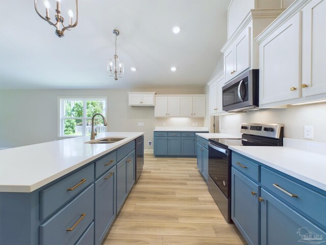 kitchen featuring white cabinets, light hardwood / wood-style floors, appliances with stainless steel finishes, decorative light fixtures, and sink