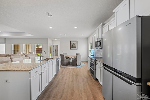 3416 Southwind Dr, Gulf Breeze, FL 32563 - kitchen featuring stainless steel appliances, a sink, light wood finished floors, white cabinets, and recessed lighting
