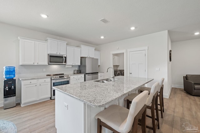 3416 Southwind Dr, Gulf Breeze, FL 32563 - kitchen with appliances with stainless steel finishes, a sink, light wood finished floors, backsplash, and an island with sink