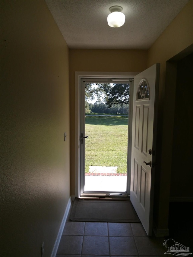 entryway featuring a textured ceiling, light tile patterned floors, and a wealth of natural light