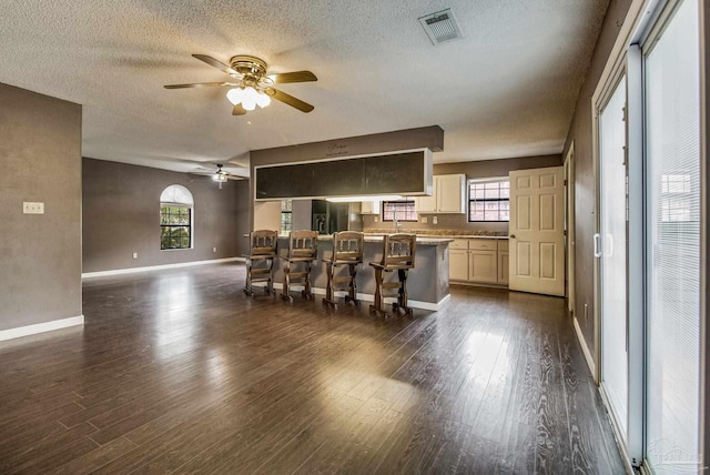 kitchen with a center island, black fridge, dark hardwood / wood-style floors, and a kitchen bar