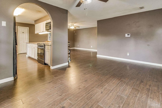 interior space featuring dark wood-type flooring, white cabinetry, a textured ceiling, electric range, and ceiling fan