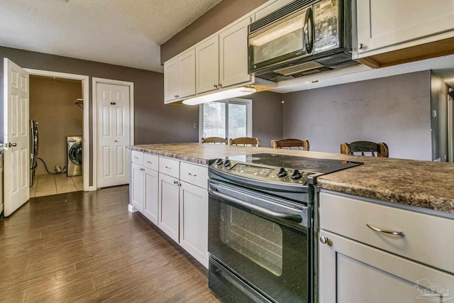 kitchen with white cabinetry, washer / clothes dryer, dark wood-type flooring, and black appliances