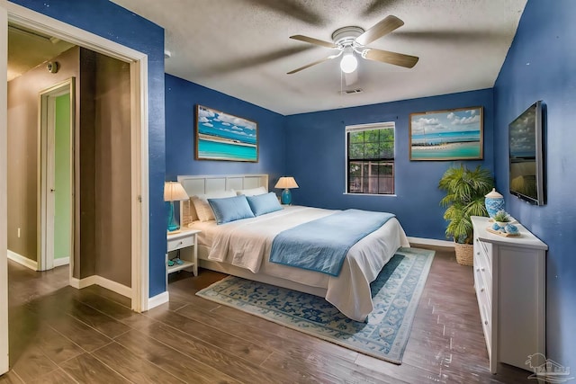 bedroom with ceiling fan, dark hardwood / wood-style flooring, and a textured ceiling