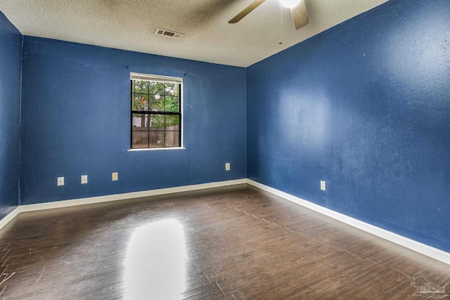 empty room featuring dark wood-type flooring, a textured ceiling, and ceiling fan