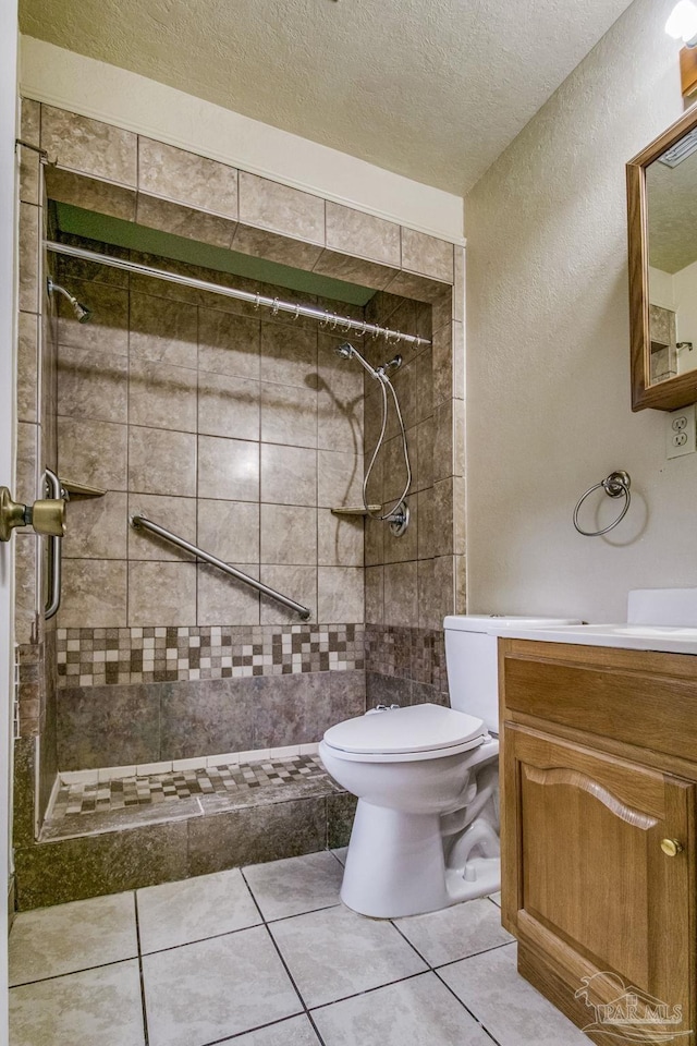 bathroom featuring tile patterned floors, toilet, a textured ceiling, a tile shower, and vanity