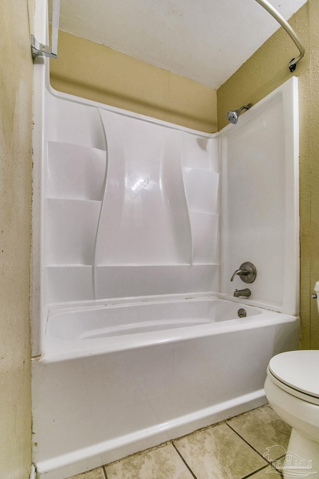 bathroom featuring tile patterned flooring, bathing tub / shower combination, and toilet