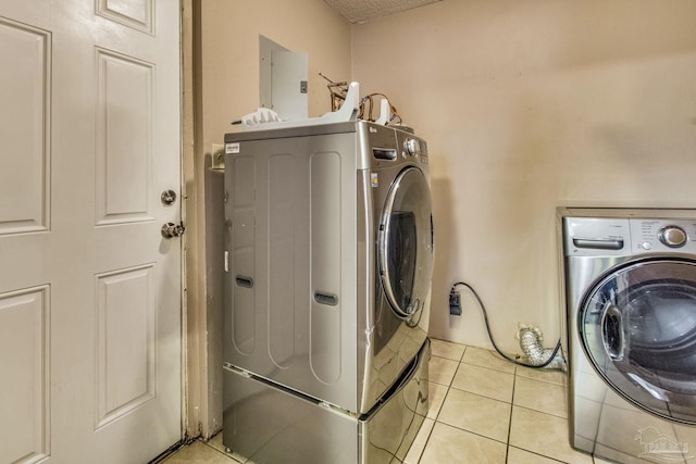 clothes washing area with light tile patterned flooring, electric panel, and washing machine and dryer