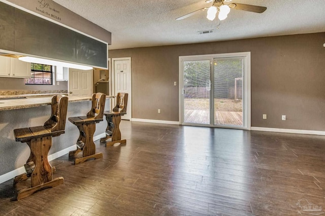 kitchen featuring ceiling fan, dark hardwood / wood-style floors, a kitchen breakfast bar, and a textured ceiling