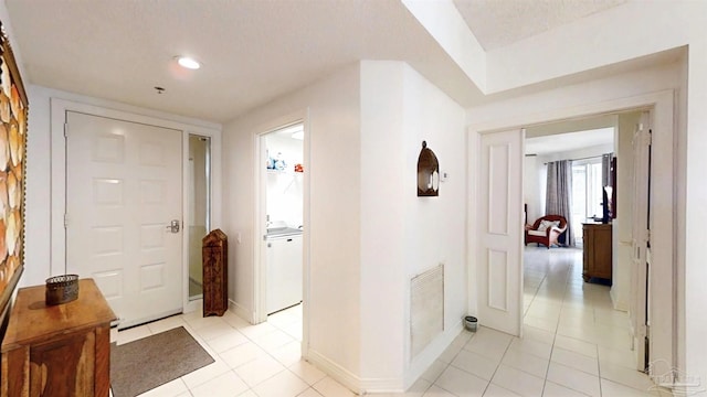 hallway featuring washer / clothes dryer and light tile patterned floors