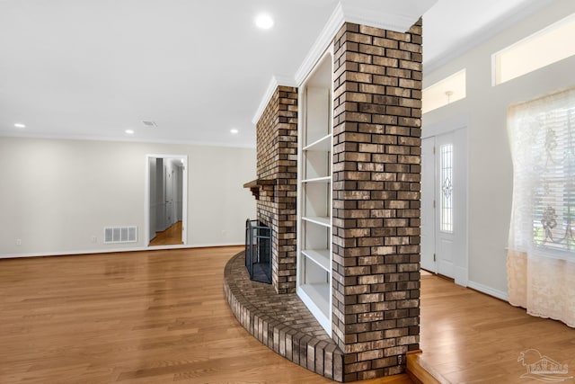 living room featuring a fireplace, light wood-type flooring, and crown molding