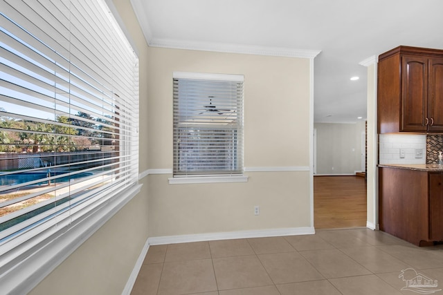 empty room featuring plenty of natural light, light tile patterned flooring, and ornamental molding