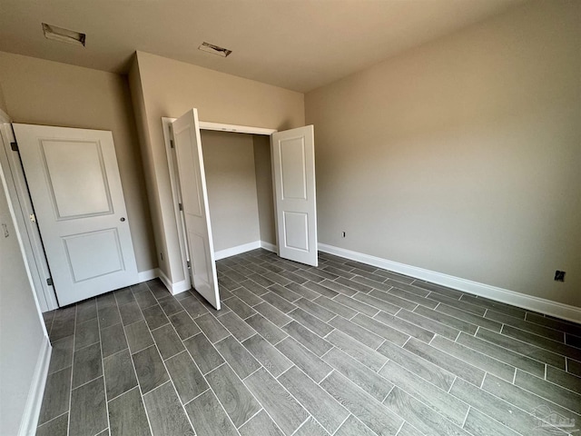 unfurnished bedroom with dark wood-style flooring, visible vents, and baseboards