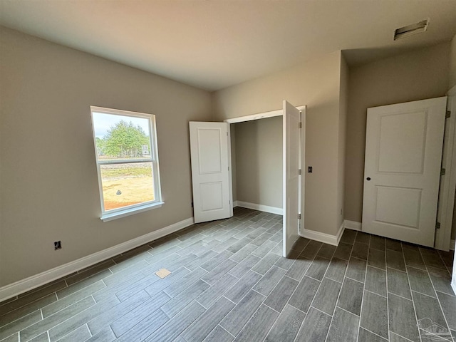 unfurnished bedroom with wood tiled floor, visible vents, and baseboards