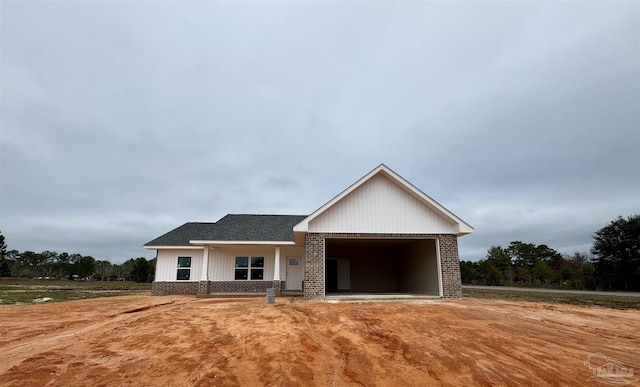 view of front facade with brick siding and roof with shingles