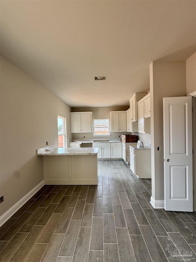 kitchen featuring visible vents, baseboards, light countertops, wood finish floors, and white cabinetry