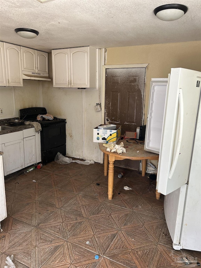 kitchen with a textured ceiling, white fridge, and black / electric stove