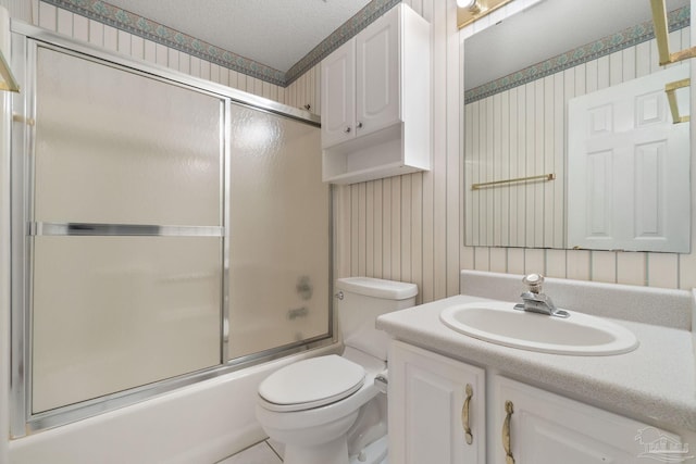 full bathroom with vanity, toilet, shower / bath combination with glass door, and a textured ceiling