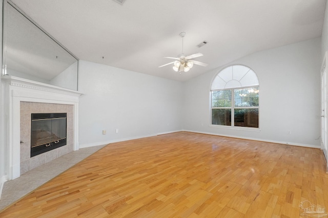 unfurnished living room with ceiling fan, lofted ceiling, a fireplace, and light hardwood / wood-style flooring