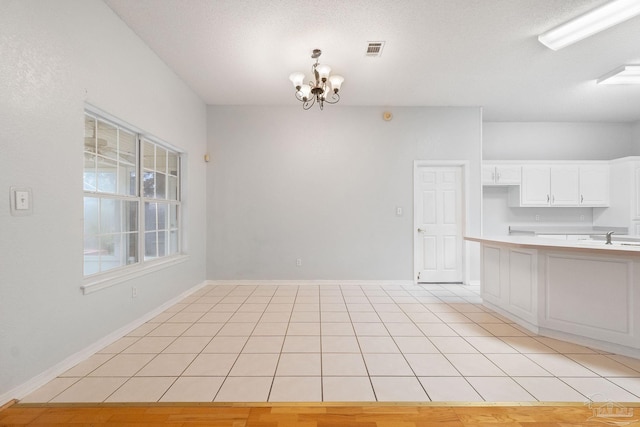 kitchen featuring pendant lighting, a notable chandelier, light tile patterned floors, and white cabinets