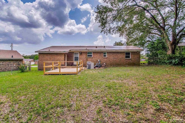 back of house featuring a deck, a yard, brick siding, and fence