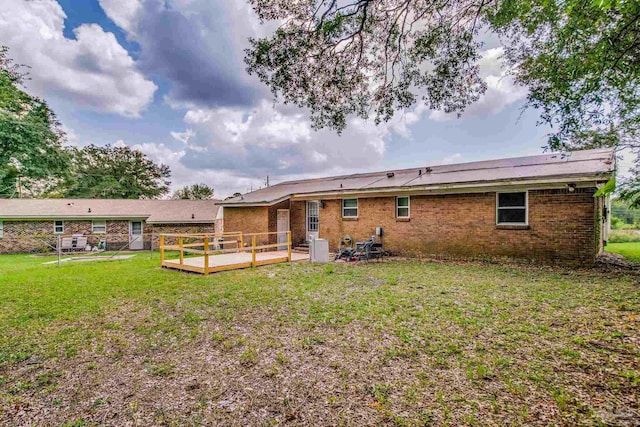 rear view of property with brick siding, a yard, and a wooden deck