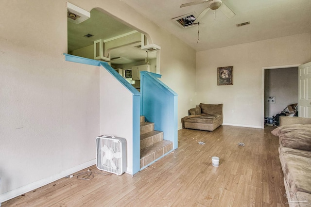 living area featuring visible vents, baseboards, ceiling fan, stairway, and wood finished floors