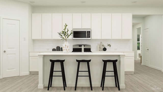 kitchen with white cabinetry and a kitchen island with sink