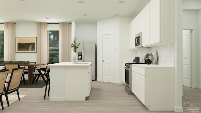 kitchen with white cabinetry, stainless steel appliances, a kitchen breakfast bar, light hardwood / wood-style flooring, and a center island with sink