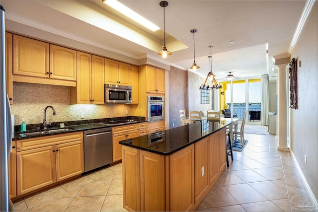 kitchen featuring stainless steel appliances, a center island, sink, ornate columns, and dark stone counters