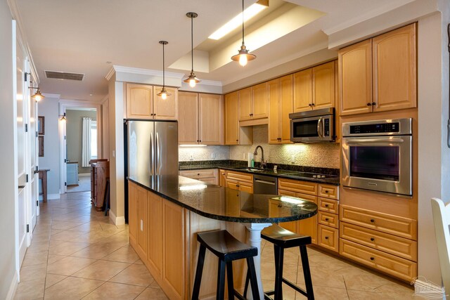 kitchen featuring stainless steel appliances, a center island, tasteful backsplash, dark stone countertops, and a breakfast bar area