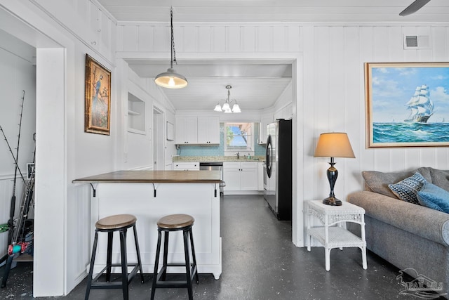 kitchen with appliances with stainless steel finishes, a sink, a chandelier, white cabinetry, and open floor plan