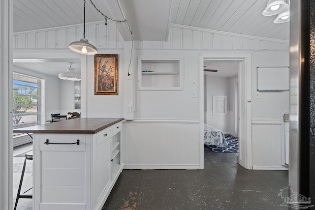 kitchen with butcher block countertops, a decorative wall, a wainscoted wall, and white cabinets