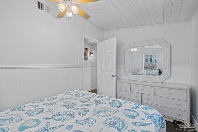 bedroom featuring ceiling fan, visible vents, and wainscoting