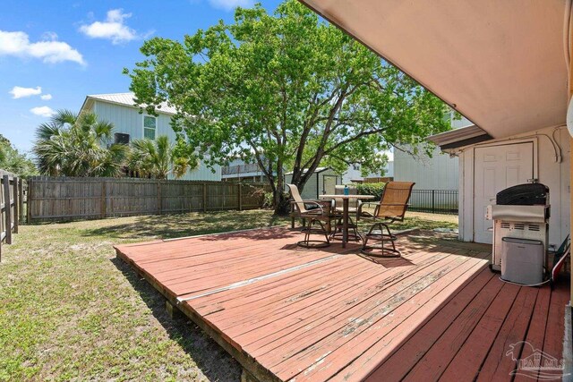 deck featuring outdoor dining area, an outdoor structure, a fenced backyard, a shed, and a yard