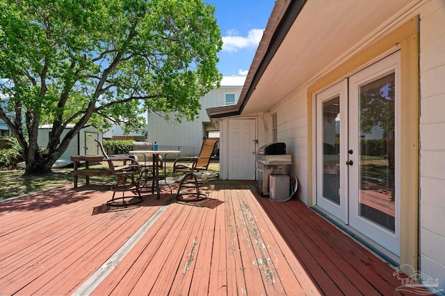 wooden deck featuring french doors, outdoor dining space, and grilling area