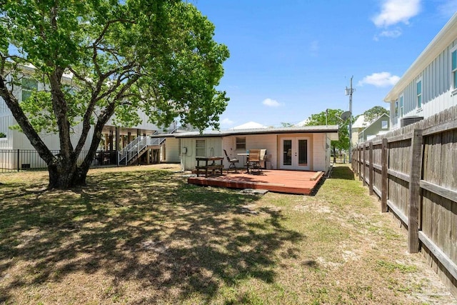 back of house with a lawn, a deck, french doors, and a fenced backyard