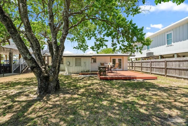 back of house with a fenced backyard, board and batten siding, a lawn, and a deck