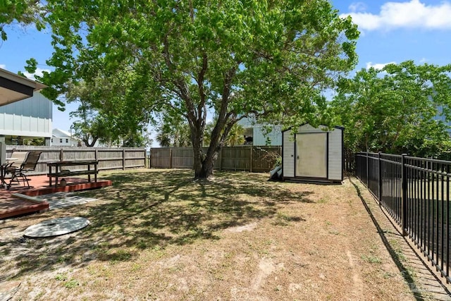 view of yard featuring an outdoor structure, a fenced backyard, a shed, and a wooden deck