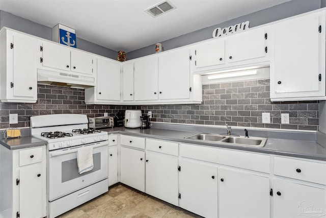 kitchen with white gas range, backsplash, sink, and white cabinets