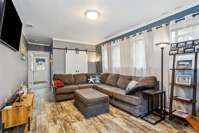 living room featuring hardwood / wood-style floors, ornamental molding, and a barn door