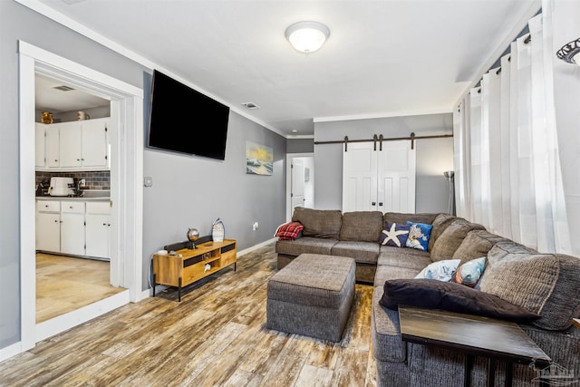 living room with ornamental molding, a barn door, and light hardwood / wood-style floors