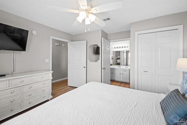 bedroom with dark wood-type flooring, ensuite bathroom, sink, a closet, and ceiling fan