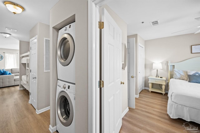 laundry room featuring light hardwood / wood-style floors, stacked washer and clothes dryer, and ceiling fan