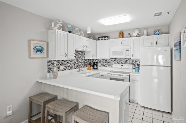 kitchen with a kitchen bar, sink, white cabinetry, kitchen peninsula, and white appliances