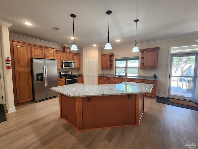 kitchen with appliances with stainless steel finishes, hanging light fixtures, a center island, and light stone counters