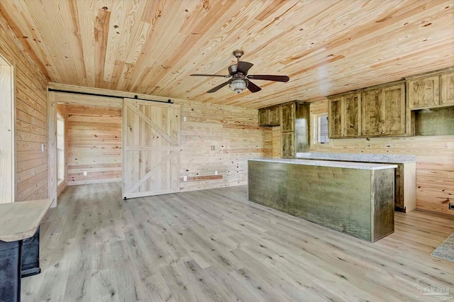 kitchen featuring wooden walls, a barn door, light wood-style flooring, a ceiling fan, and wood ceiling