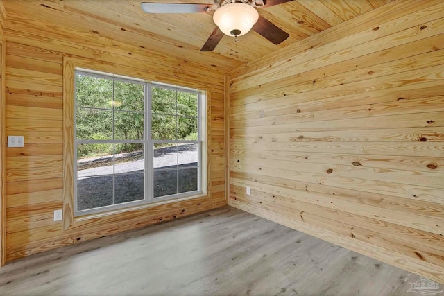 unfurnished room featuring wood walls, a ceiling fan, wood finished floors, and wooden ceiling